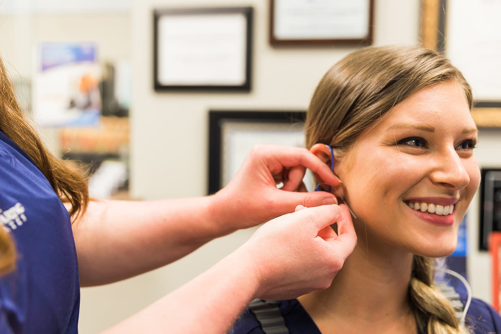 A team member of Alabama Hearing Associates demonstrating how to adjust to a new hearing aid